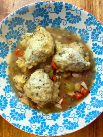 Chicken and dumplings served in a decorative blue and white bowl.