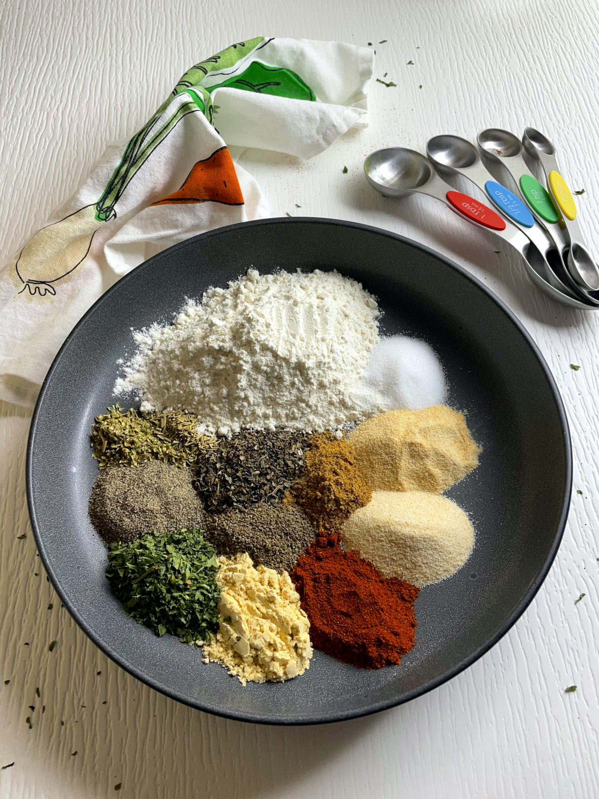 Piles of spices used for making stew mix placed decoratively around a plate. It contains ground mustard, paprika, parsley, cumin, flour and other spices.