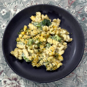 A plate of cheesy noodles made with spiral noodles, cheese and brocoli