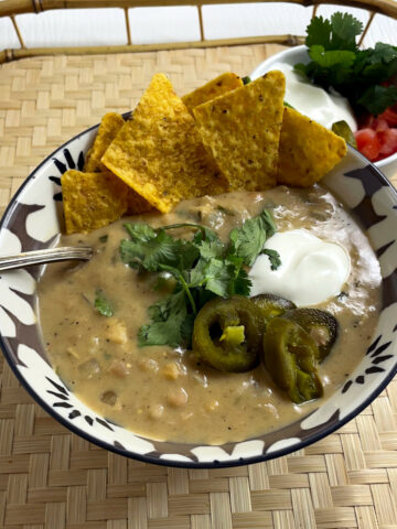 Bowl of white chicken chili topped with sour cream, jalapeños and cilantro