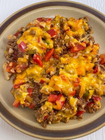 Stuffed pepper skillet made with ground beef and diced peppers covered in melted cheese served on a vintage brown plate