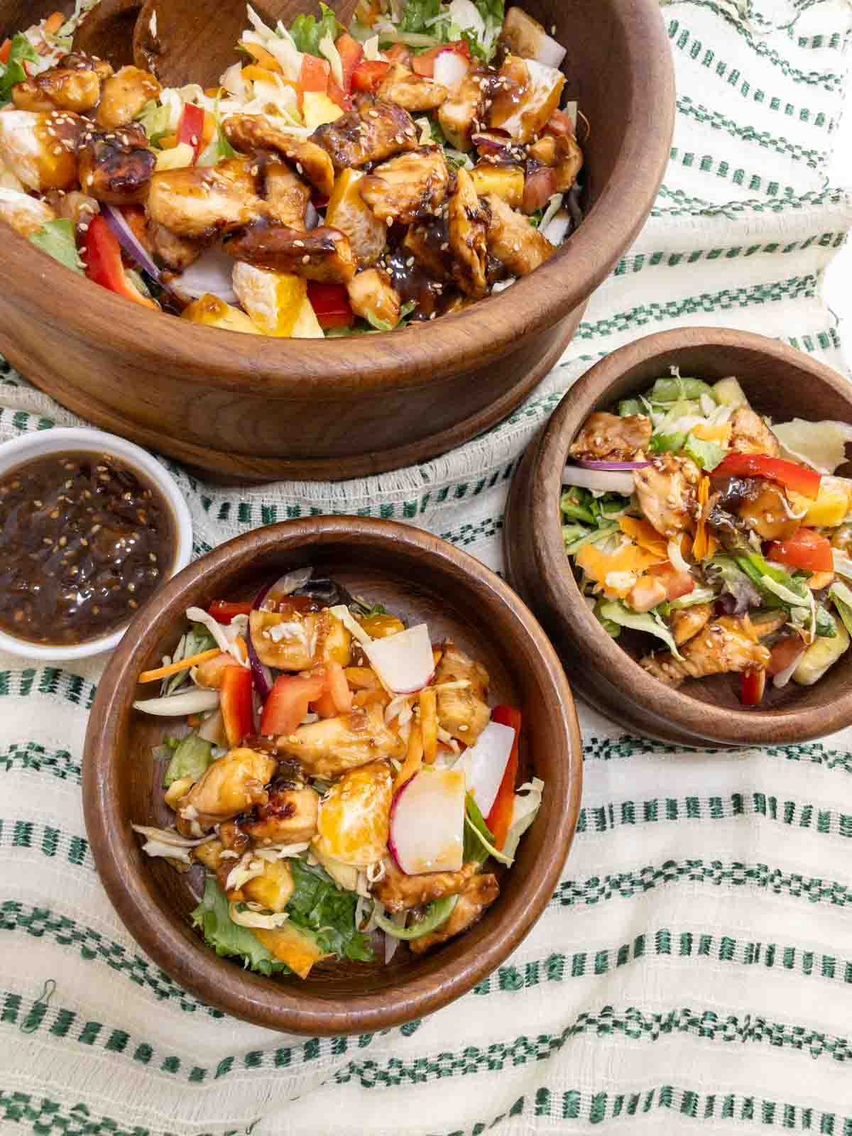 Teriyaki chicken salad served in a teak wood bowl. Tender chuncks of chicken glazed with teriyaki sauce over lettuce peppers and onions.